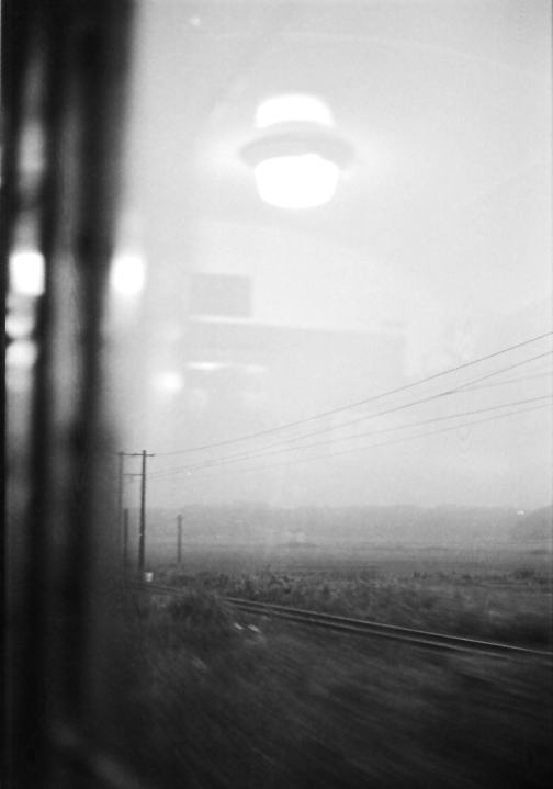 夕暮れの東北本線八戸あたり。窓ガラスに映った車内の白熱灯
