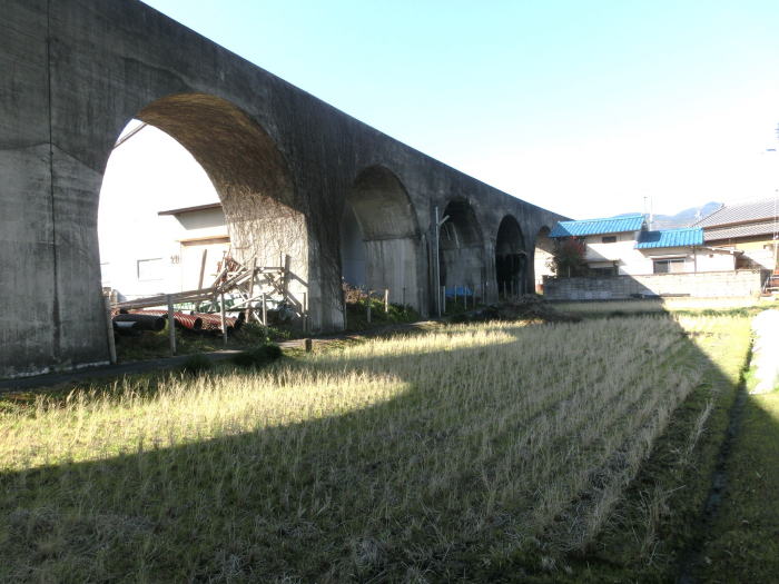 田んぼにアーチ型の高架橋の影